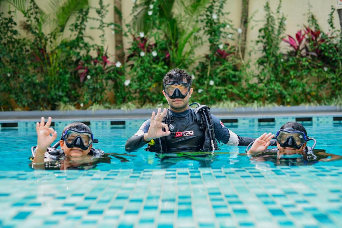 a man and two children in a swimming pool at Holiday Inn Goa Candolim in Candolim a man and two children in a swimming pool at Holiday Inn Goa Candolim in Candolim