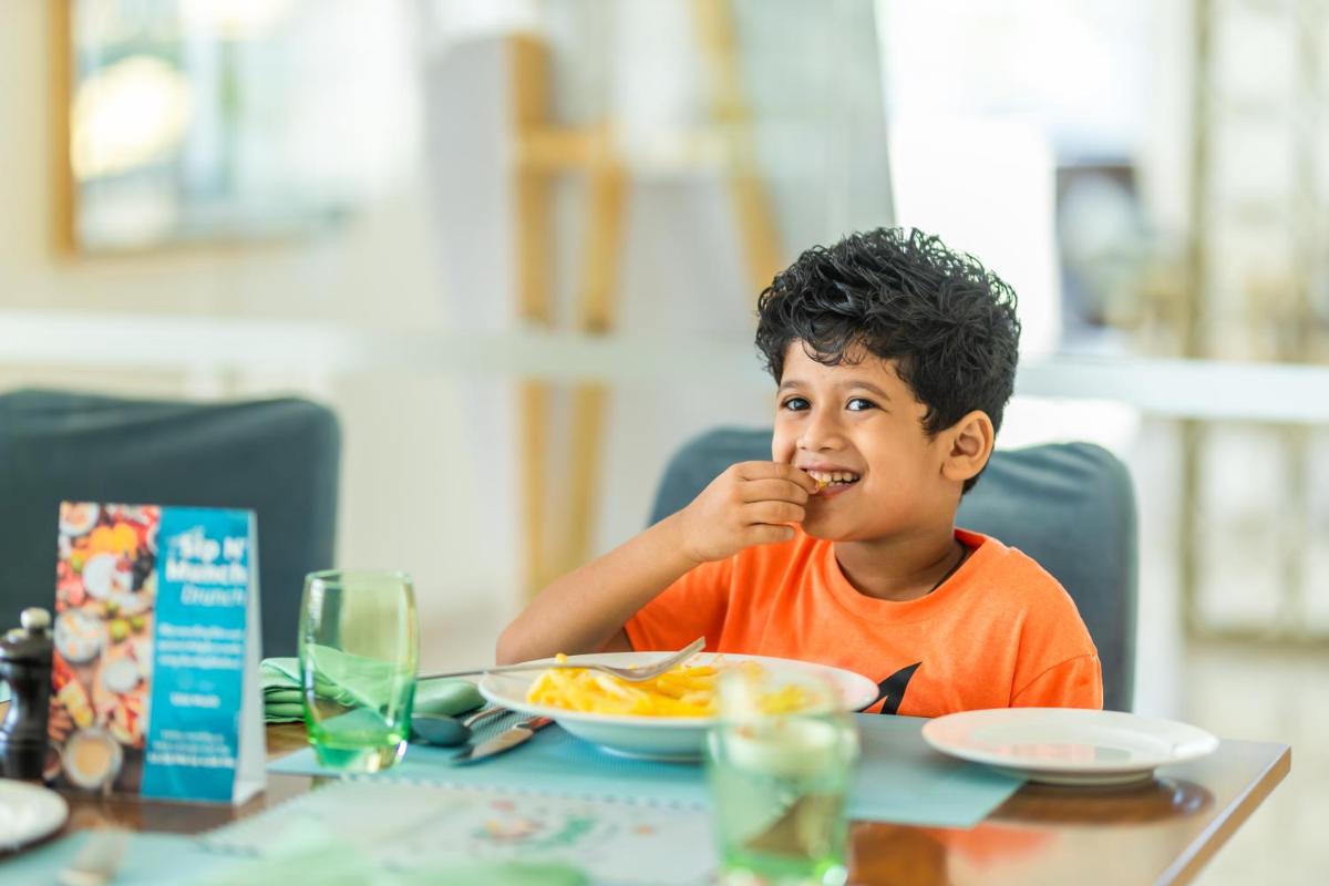 a young boy sitting at a table eating food at Holiday Inn Goa Candolim in Candolim a young boy sitting at a table eating food at Holiday Inn Goa Candolim in Candolim