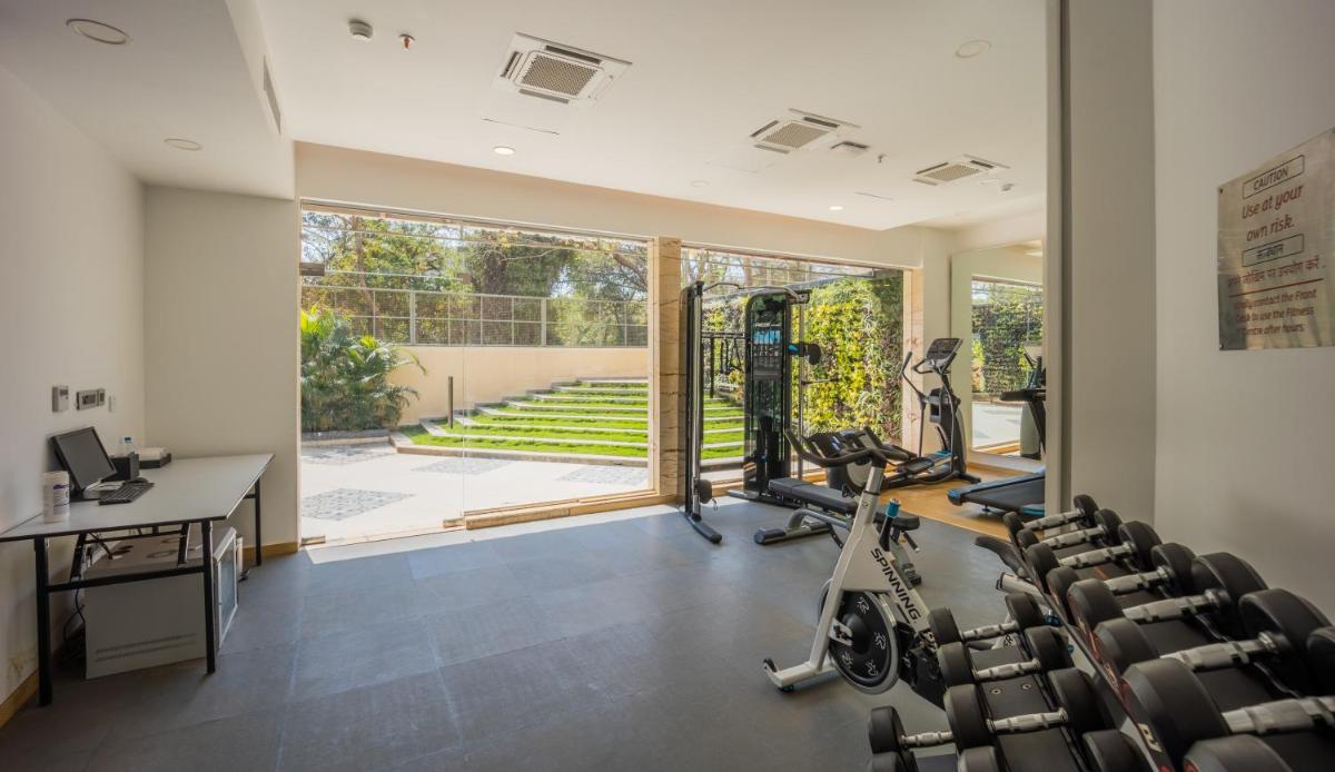 a gym with cardio equipment and a desk and chairs at Holiday Inn Goa Candolim in Candolim a gym with cardio equipment and a desk and chairs at Holiday Inn Goa Candolim in Candolim