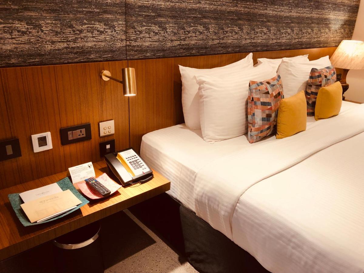 a hotel room with a bed and a table with a phone at Casino Hotel - CGH Earth, Cochin in Cochin