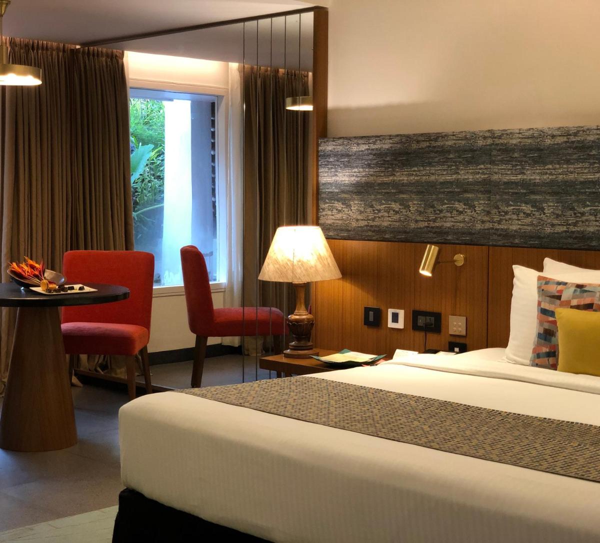 a hotel room with a bed and a table and a window at Casino Hotel - CGH Earth, Cochin in Cochin