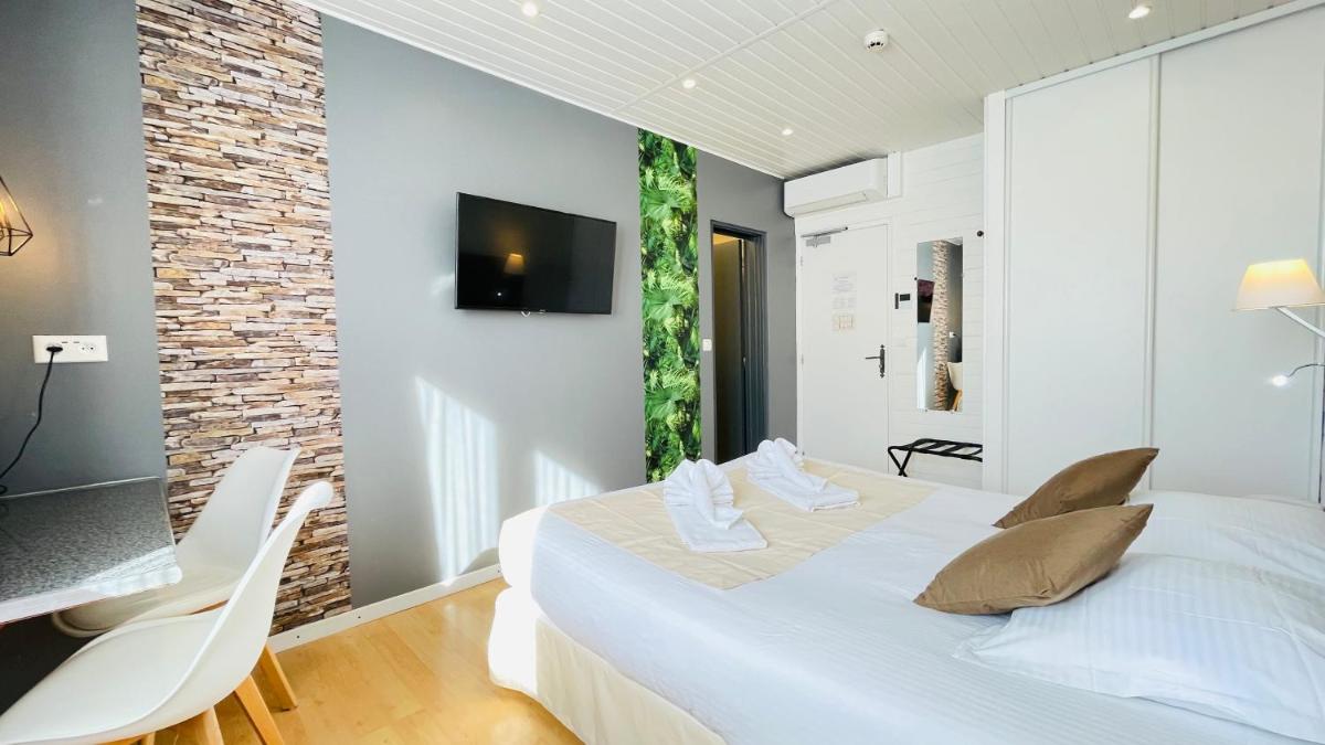 une chambre avec un lit, un bureau et une télévision dans l'établissement Auberge de la Petite Reine, à Siorac-en-Périgord