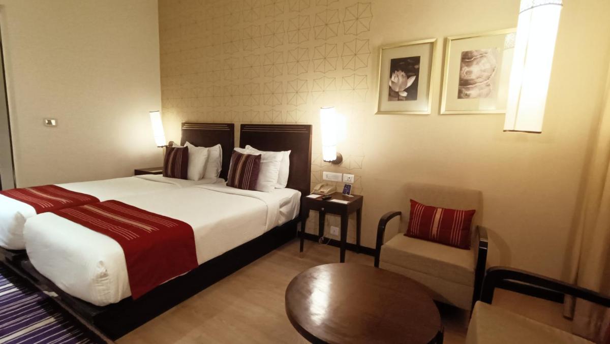 a hotel room with a bed and a table and a chair at Marasa Sarovar Premiere in Tirupati