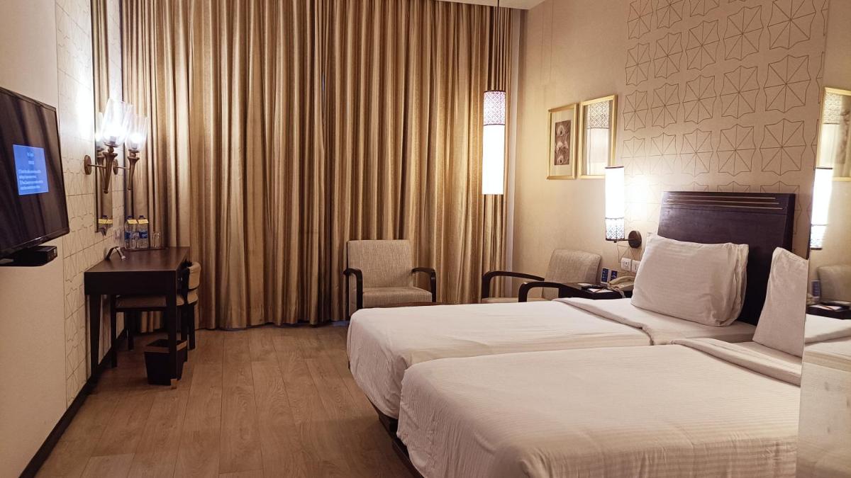 a hotel room with two beds and a desk at Marasa Sarovar Premiere in Tirupati