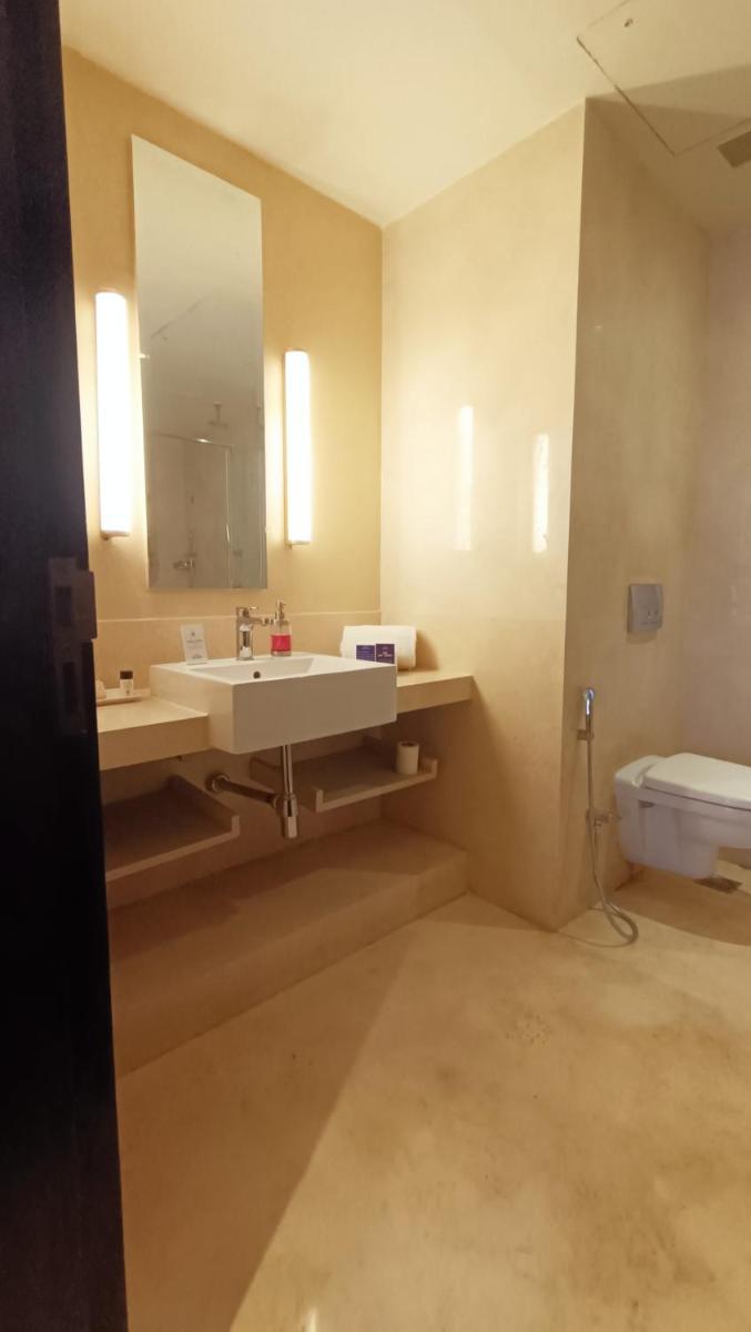 a bathroom with a sink and a mirror and a toilet at Marasa Sarovar Premiere in Tirupati