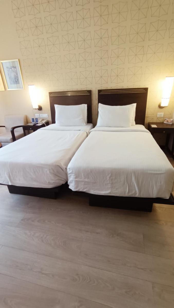 two beds in a hotel room with white sheets and pillows at Marasa Sarovar Premiere in Tirupati