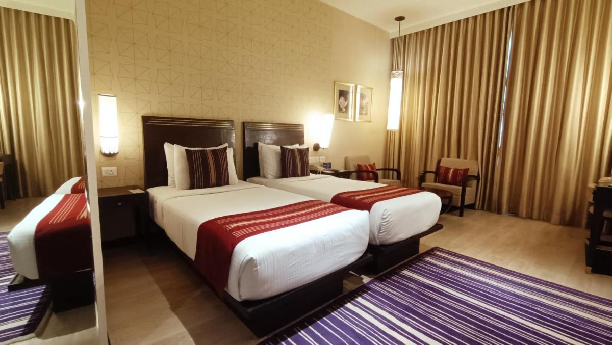 a hotel room with two beds and a mirror at Marasa Sarovar Premiere in Tirupati