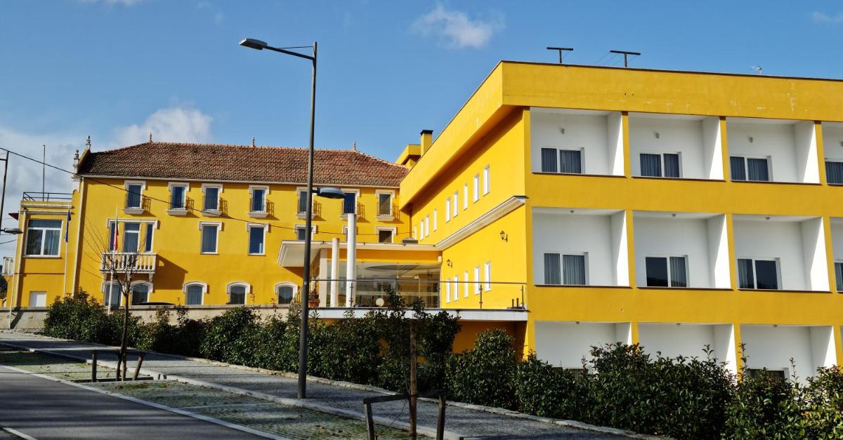 um edifício amarelo e branco ao lado de uma rua em Palace Hotel Astúrias & Spa em Carvalhal