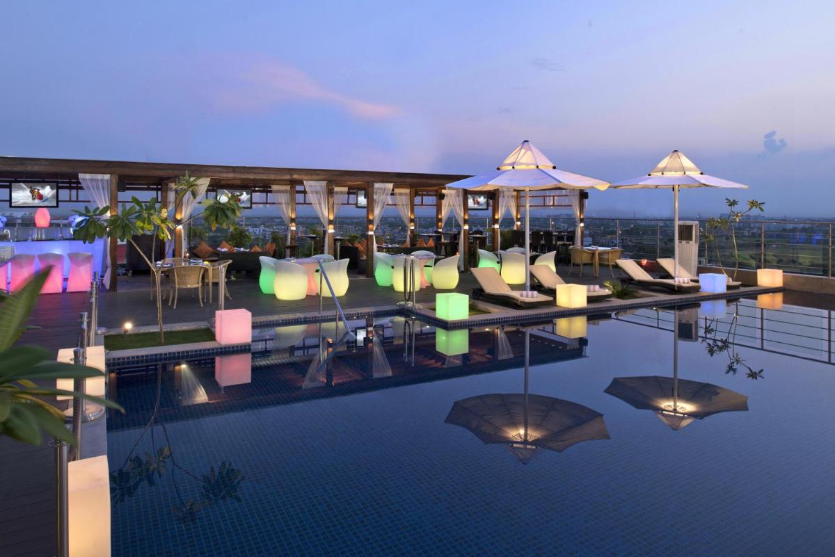 a swimming pool with chairs and umbrellas on a building at Radisson Blu Jaipur in Jaipur