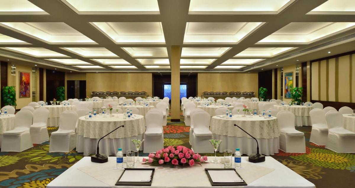 a banquet hall with white tables and white chairs at Radisson Blu Jaipur in Jaipur