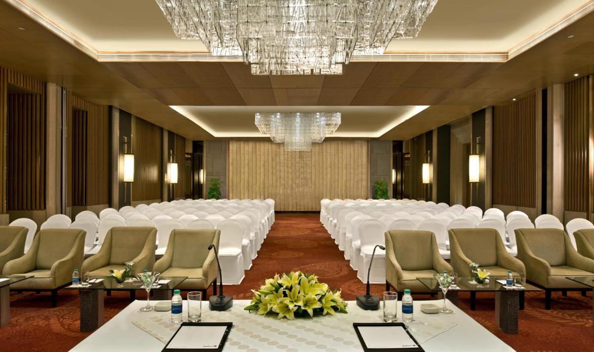 a conference room with white tables and chairs and a chandelier at Radisson Blu Jaipur in Jaipur +72 photos
