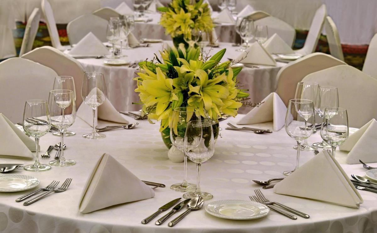a white table with a vase of yellow flowers on it at Radisson Blu Jaipur in Jaipur
