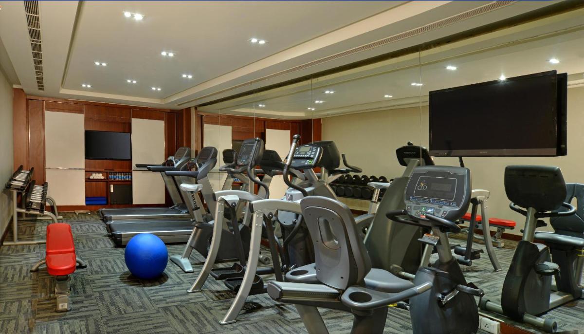 a gym with a bunch of exercise equipment and a flat screen tv at Radisson Blu Jaipur in Jaipur