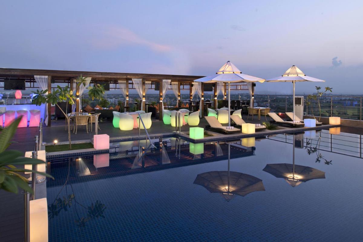 a pool with chairs and umbrellas on top of a building at Radisson Blu Jaipur in Jaipur