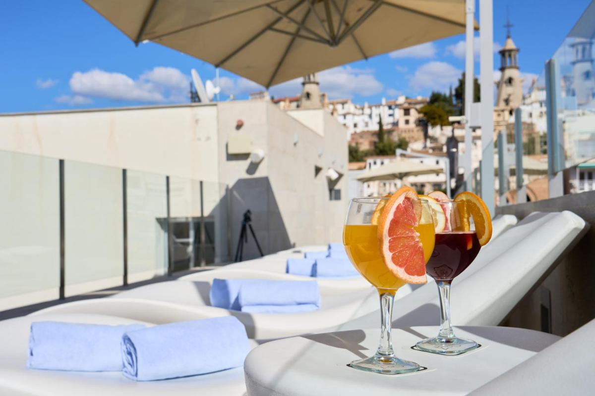 dos copas de vino en una mesa en un balcón en Hotel Maciá Granada Five Senses Rooms & Suites, en Granada