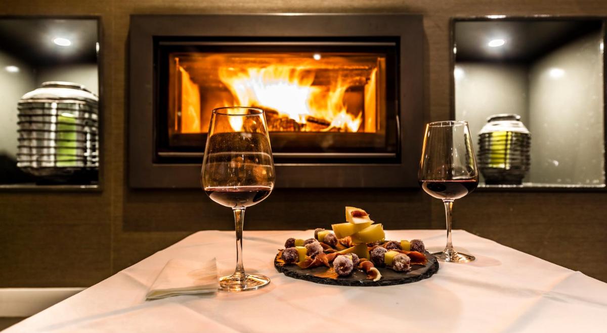 dois copos de vinho e um prato de comida numa mesa com lareira em Grande Hotel das Caldas da Felgueira nas Caldas da Felgueira