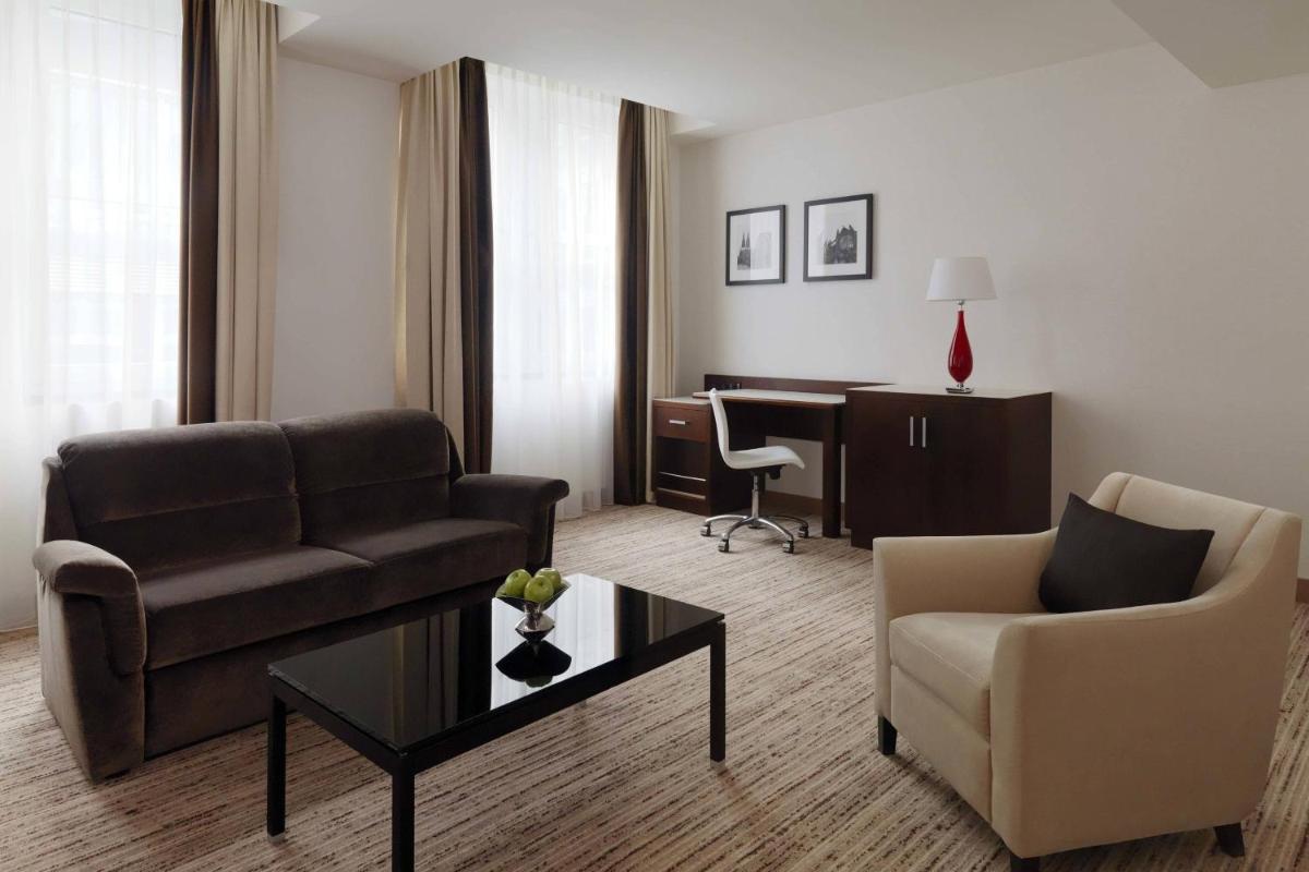 ein Wohnzimmer mit einer Couch, einem Sessel und einem Tisch in der Unterkunft Cologne Marriott Hotel in Köln ein Wohnzimmer mit einer Couch, einem Sessel und einem Tisch in der Unterkunft Cologne Marriott Hotel in Köln