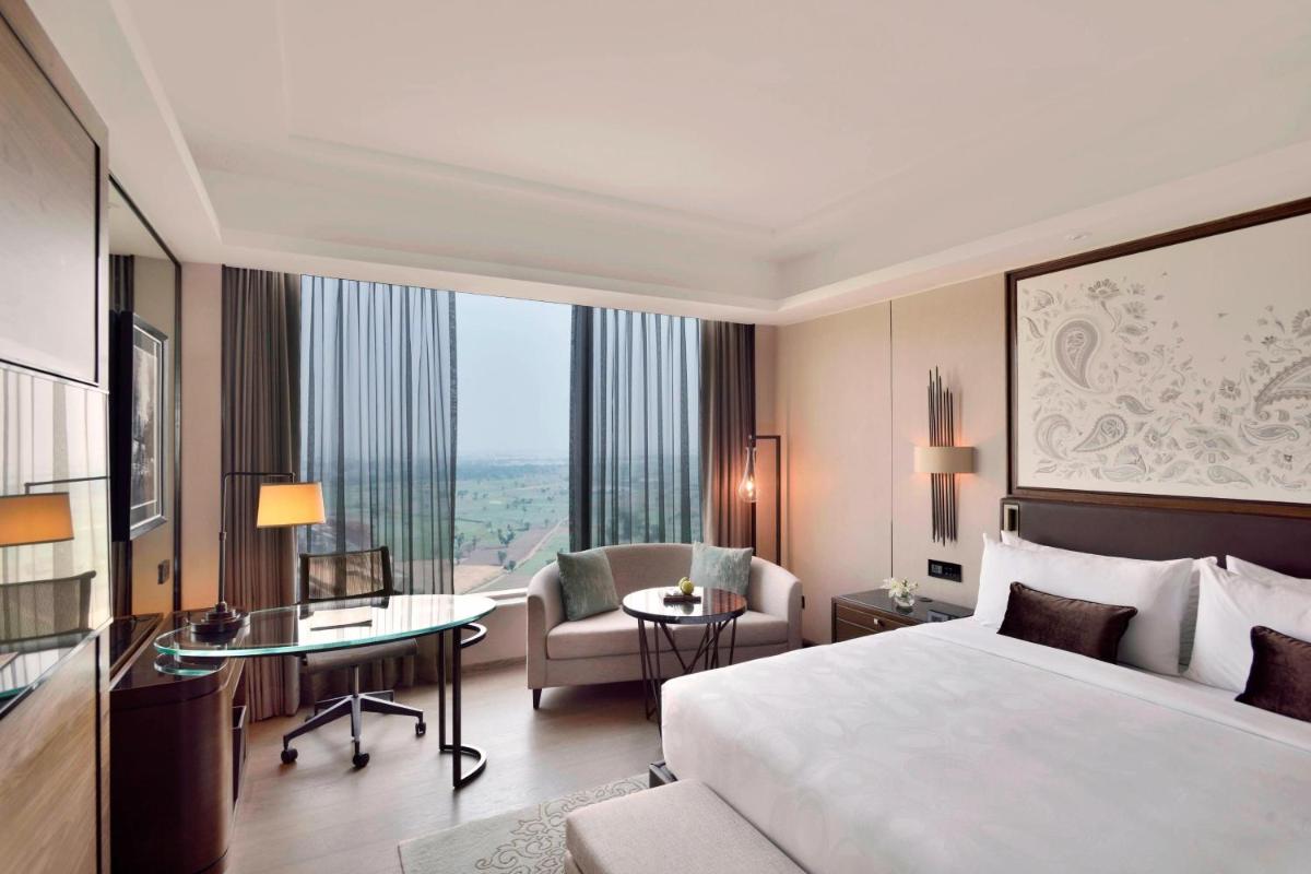a hotel room with a bed and a desk and a chair at JW Marriott Hotel Kolkata in Kolkata