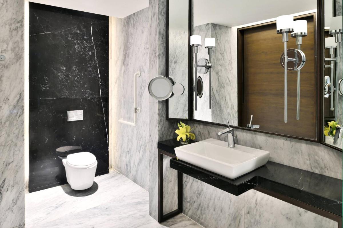 a bathroom with a sink and a toilet and a mirror at JW Marriott Hotel Kolkata in Kolkata