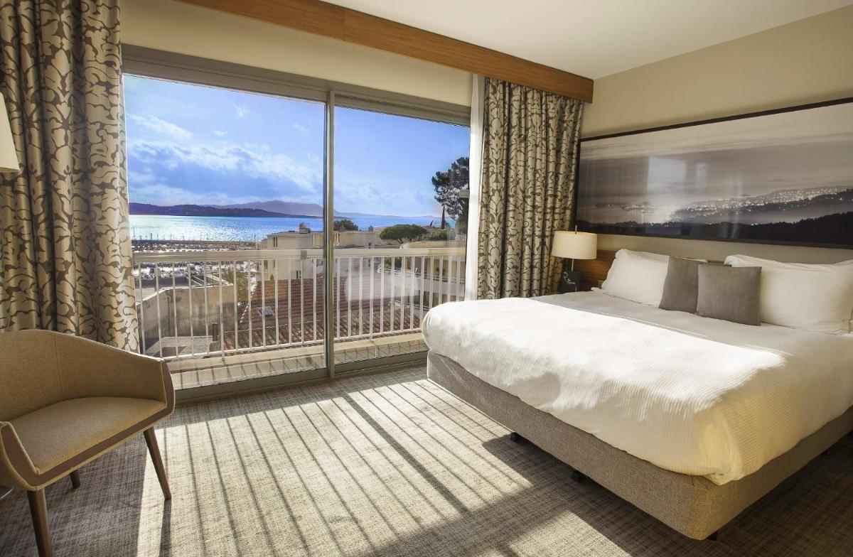 une chambre d'hôtel avec un lit et une grande fenêtre dans l'établissement Thalazur Bandol Ile Rousse - Hôtel & Spa, à Bandol