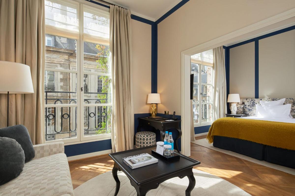 une chambre d'hôtel avec un lit, un canapé et une table dans l'établissement Le Pavillon de la Reine & Spa, Place des Vosges, à Paris