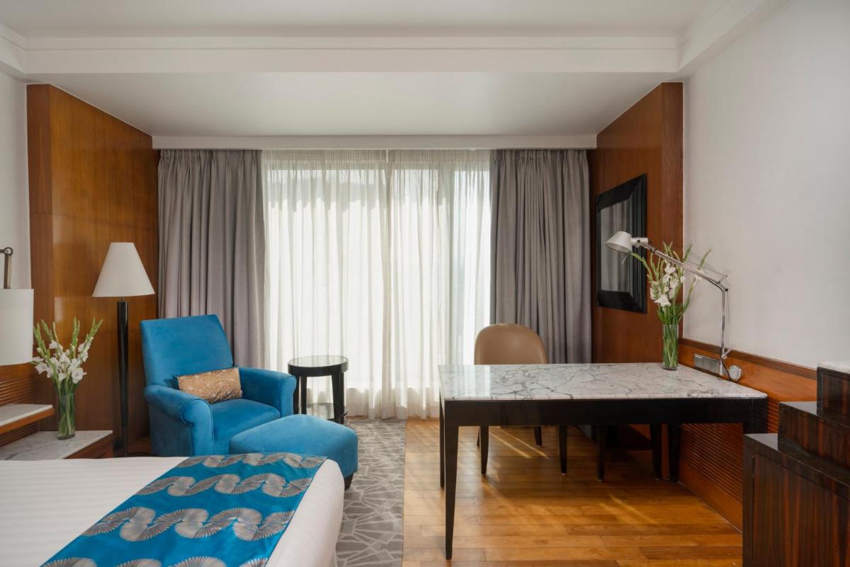 a hotel room with a bed and a dining room at InterContinental Marine Drive Mumbai by IHG in Mumbai