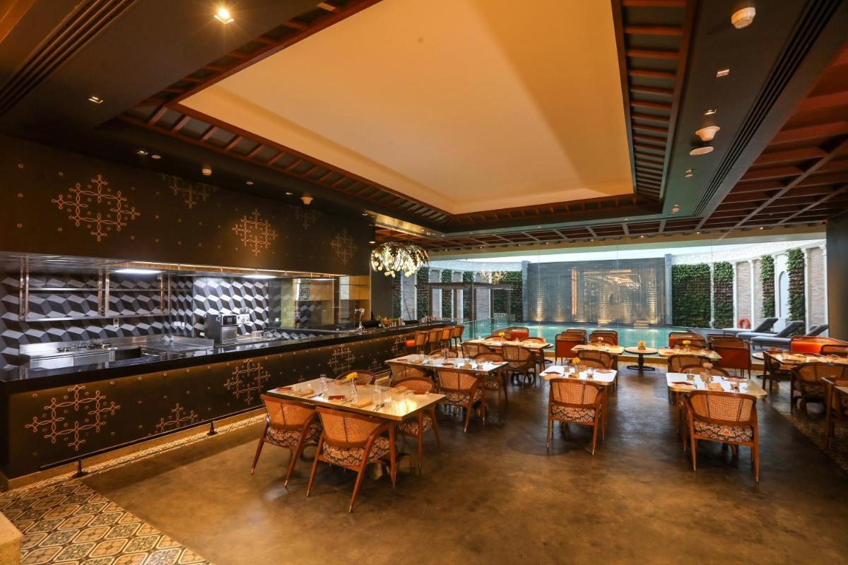 a restaurant with tables and chairs and a bar at Radisson Blu Hotel & Suites GRT Chennai in Chennai