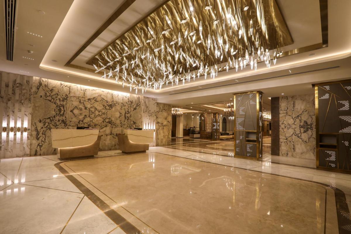 a lobby with a bar with a chandelier at Radisson Blu Hotel & Suites GRT Chennai in Chennai