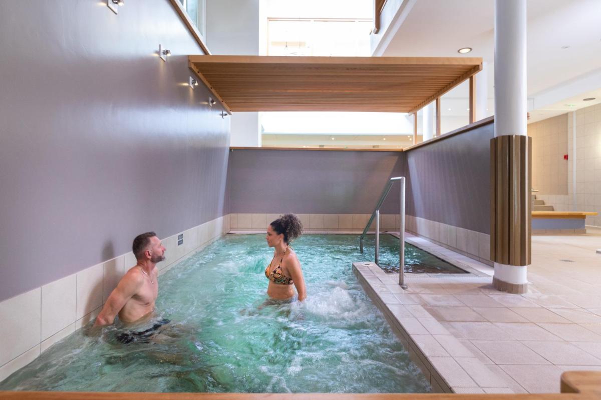 un homme et une femme dans une piscine dans l'établissement Hotel & Spa Radiana, à La Léchère