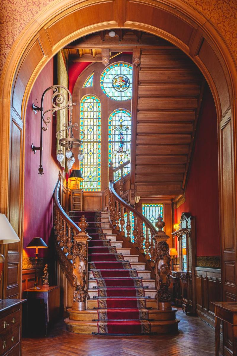 un escalier en colimaçon dans un bâtiment doté d'un vitrail dans l'établissement Château La Comtesse de Loire & Spa, à Saumur