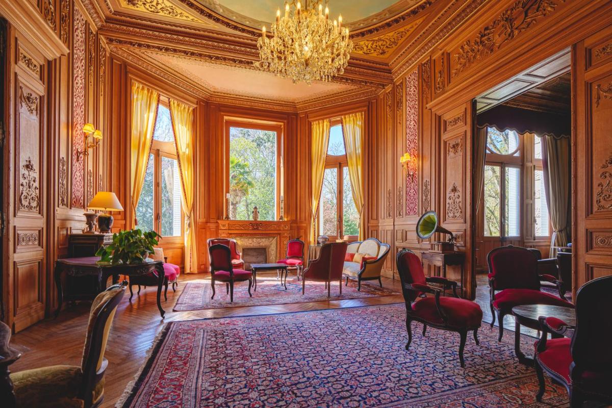 une pièce avec des chaises, des tables et un lustre dans l'établissement Château La Comtesse de Loire & Spa, à Saumur