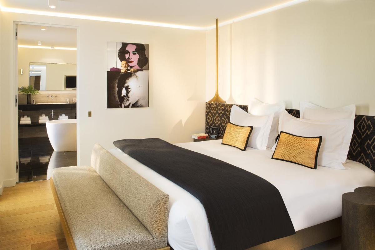 une chambre avec un grand lit blanc et une salle de bain dans l'établissement Hotel Marignan Champs-Elysées, à Paris