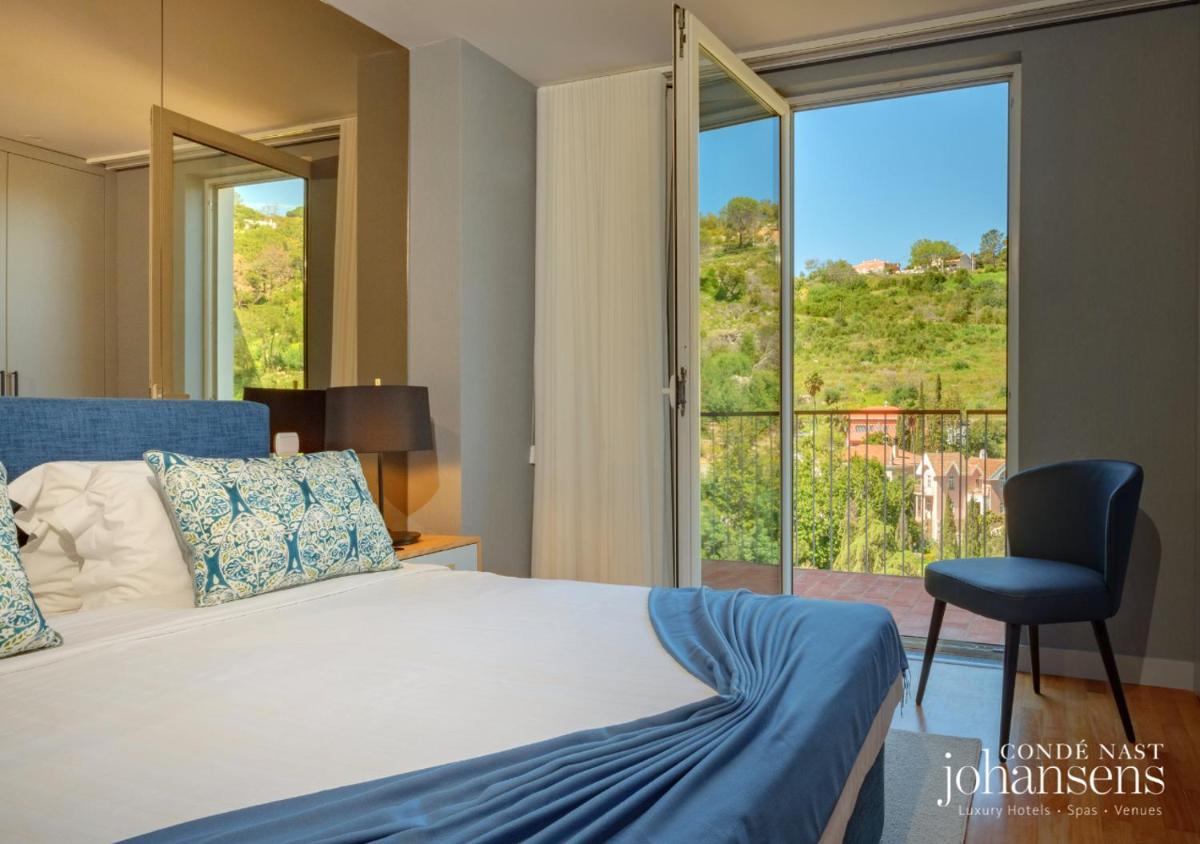 um quarto com uma cama, uma cadeira e uma janela em Pure Monchique Hotel - Villa Termal Spa Resort - by Unlock Hotels em Monchique