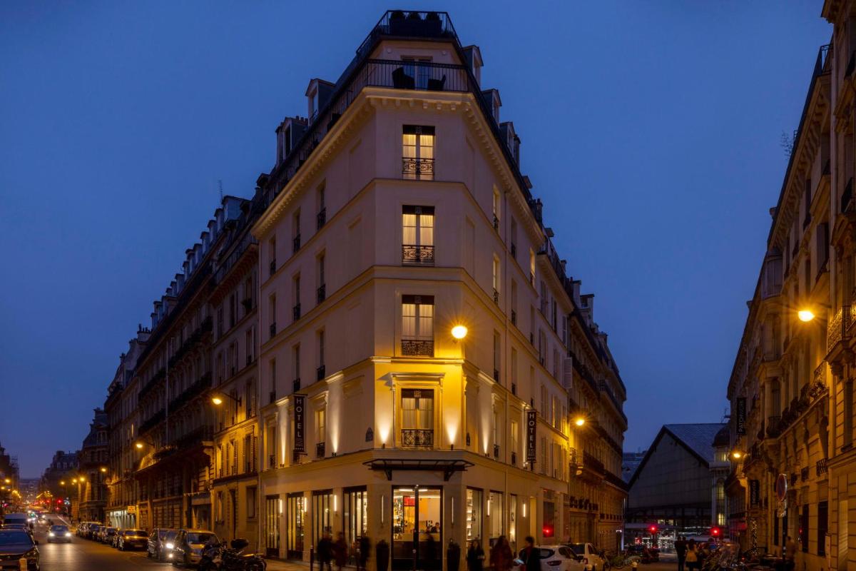 un grand bâtiment blanc sur une rue de la ville la nuit dans l'établissement Le 12 Hôtel, à Paris
