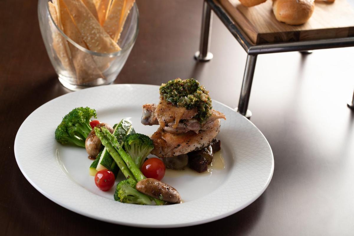 a white plate of food with vegetables on a table at Holiday Inn Agra MG Road an IHG Hotel in Agra