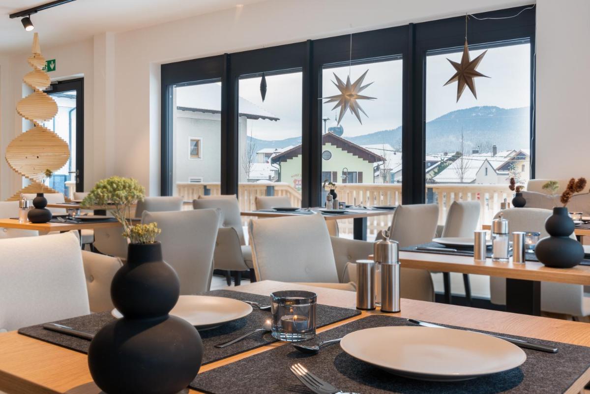 ein Esszimmer mit Tischen und Stühlen und großen Fenstern in der Unterkunft zeitlang by Rösslwirt in Lam