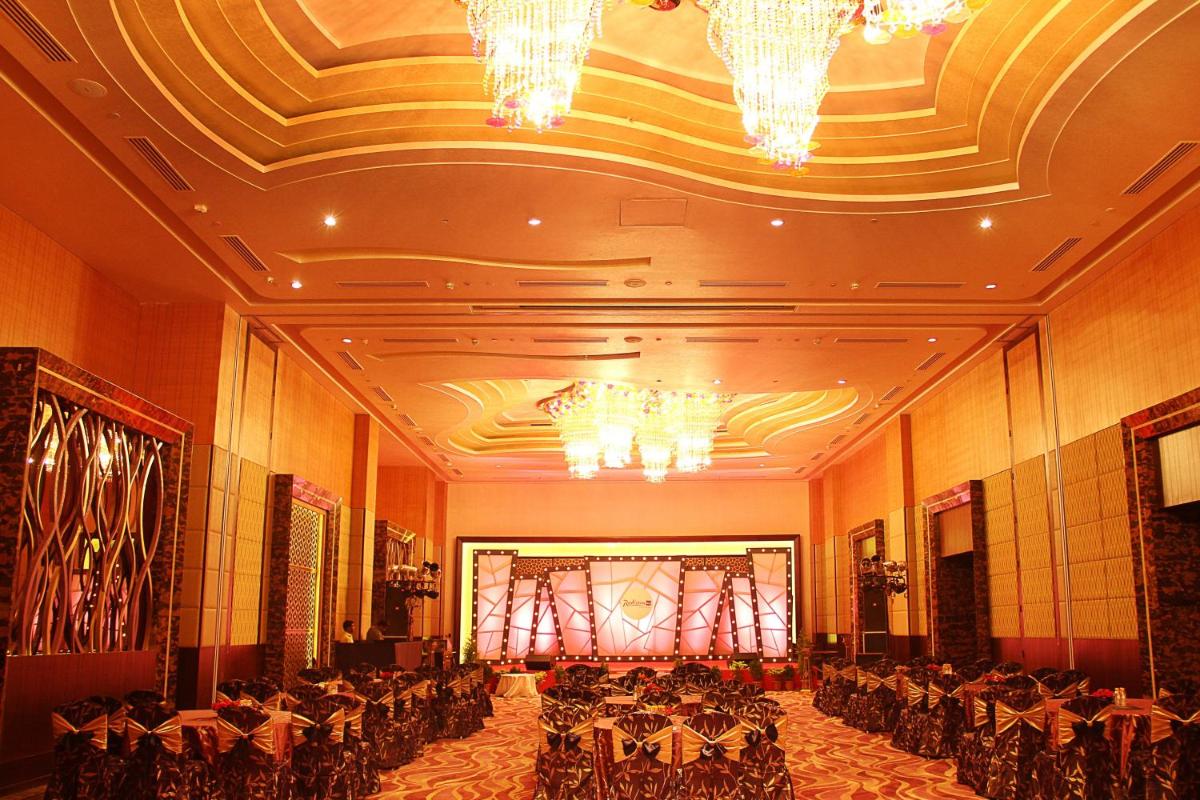 a banquet hall with tables and chairs and chandeliers at Radisson Blu Hotel, Indore in Indore