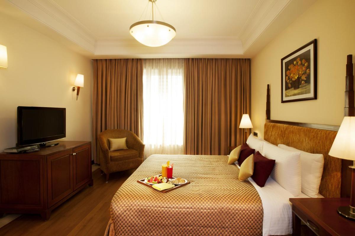 a hotel room with a bed with a tray of food on it at The Accord Metropolitan in Chennai