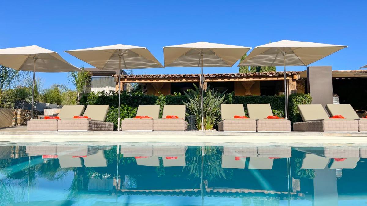 une piscine avec parasols et chaises longues à côté d'une maison dans l'établissement Hôtel La Dimora & Spa, à Saint-Florent