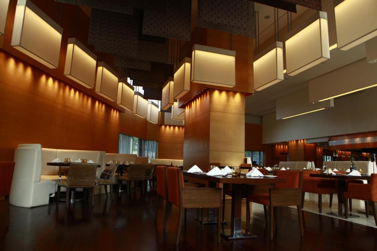 a dining room with tables and chairs and lights at Novotel Pune Viman Nagar Road in Pune