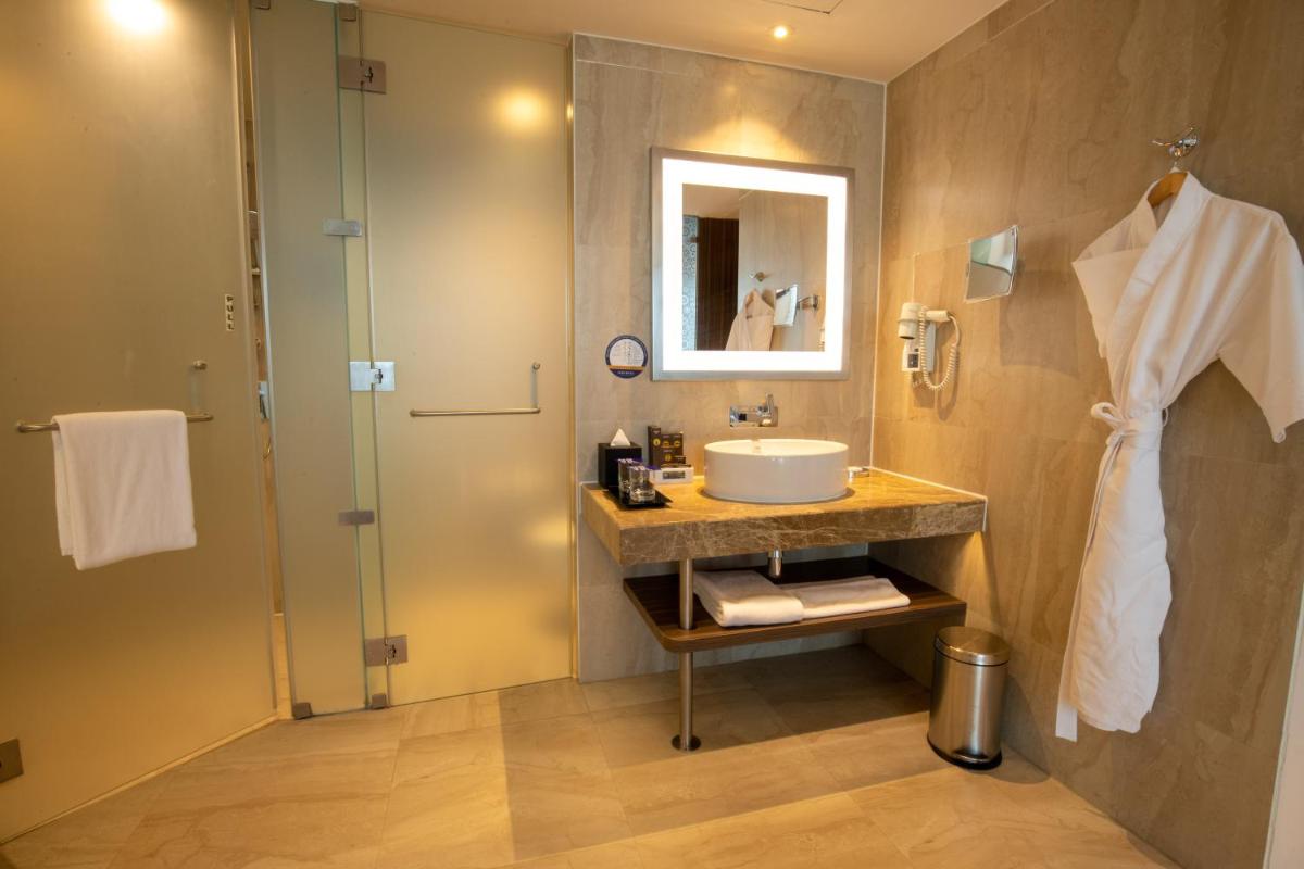 a bathroom with a sink and a shower at Novotel Pune Viman Nagar Road in Pune