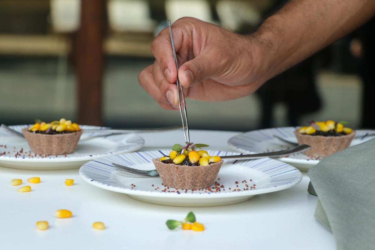 a person holding a fork and knife over a plate of food at Crowne Plaza Pune City Centre by IHG in Pune