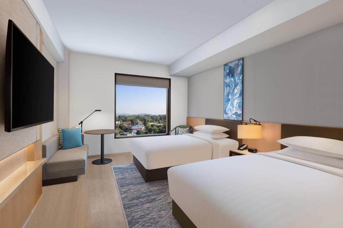 a hotel room with two beds and a large window at Fairfield by Marriott Dehradun in Dehradun