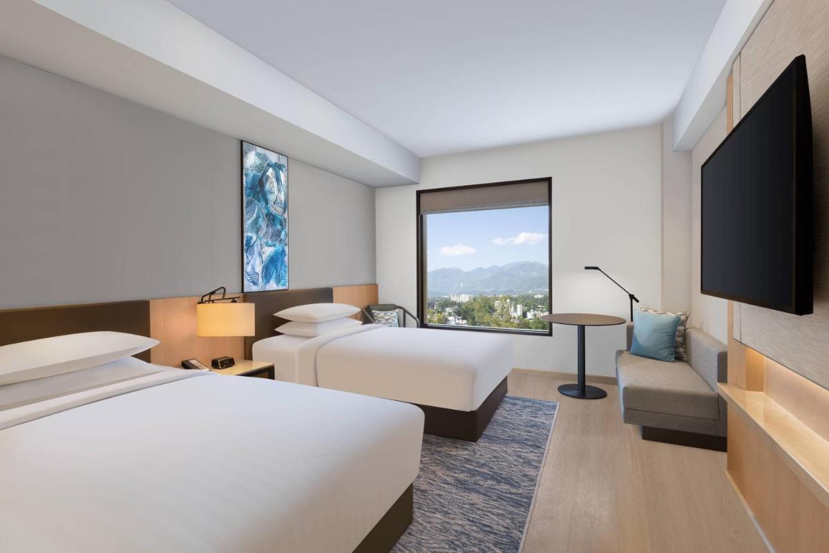 a hotel room with two beds and a large window at Fairfield by Marriott Dehradun in Dehradun