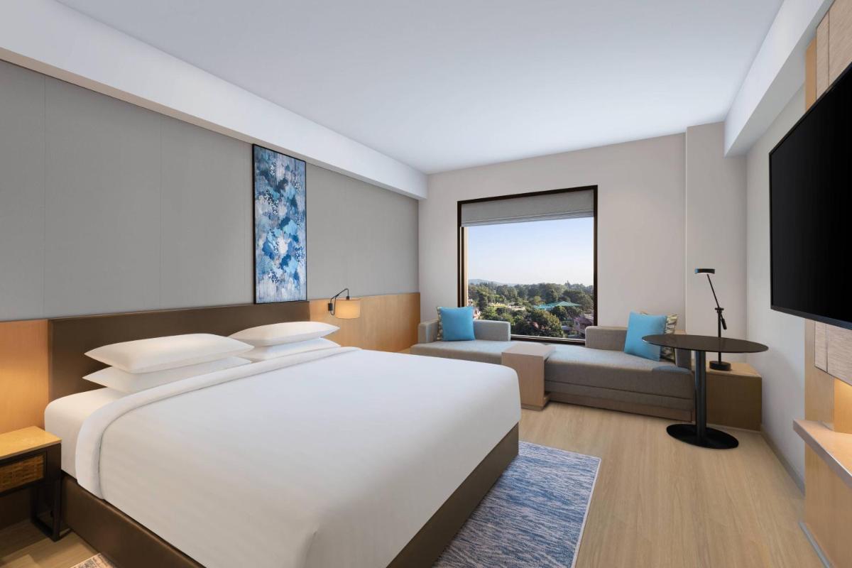 a bedroom with a large bed and a living room at Fairfield by Marriott Dehradun in Dehradun