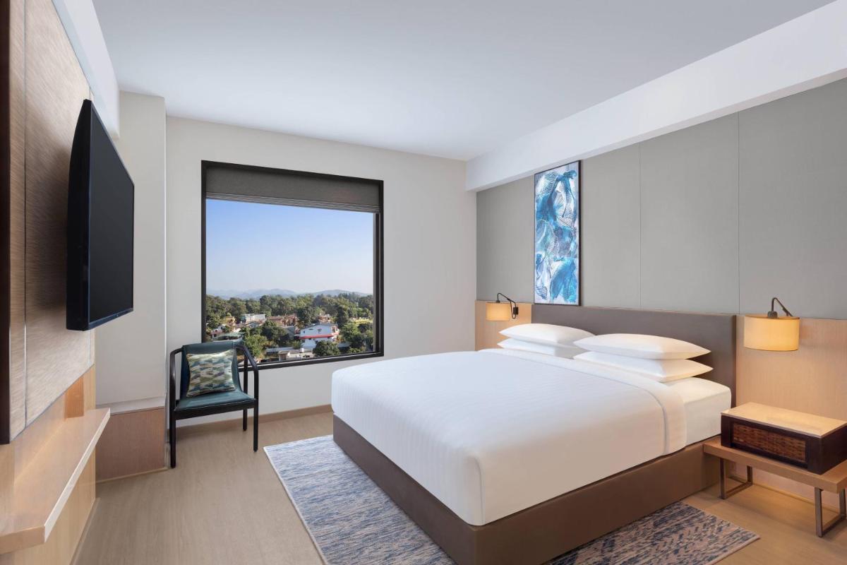 a bedroom with a white bed and a large window at Fairfield by Marriott Dehradun in Dehradun
