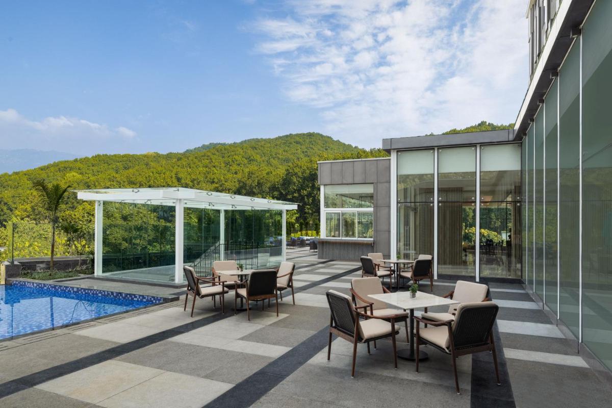 a patio with tables and chairs next to a pool at Fairfield by Marriott Dehradun in Dehradun