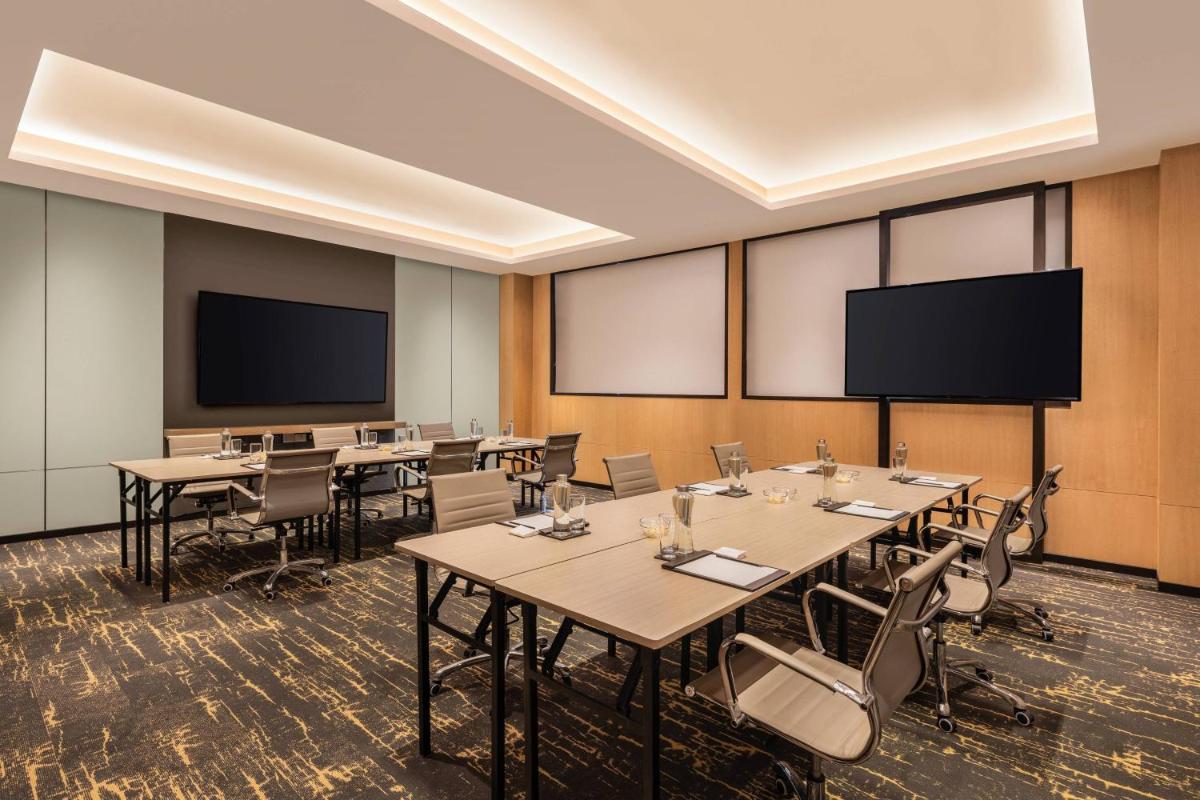 a conference room with tables and chairs and a projection screen at Fairfield by Marriott Dehradun in Dehradun