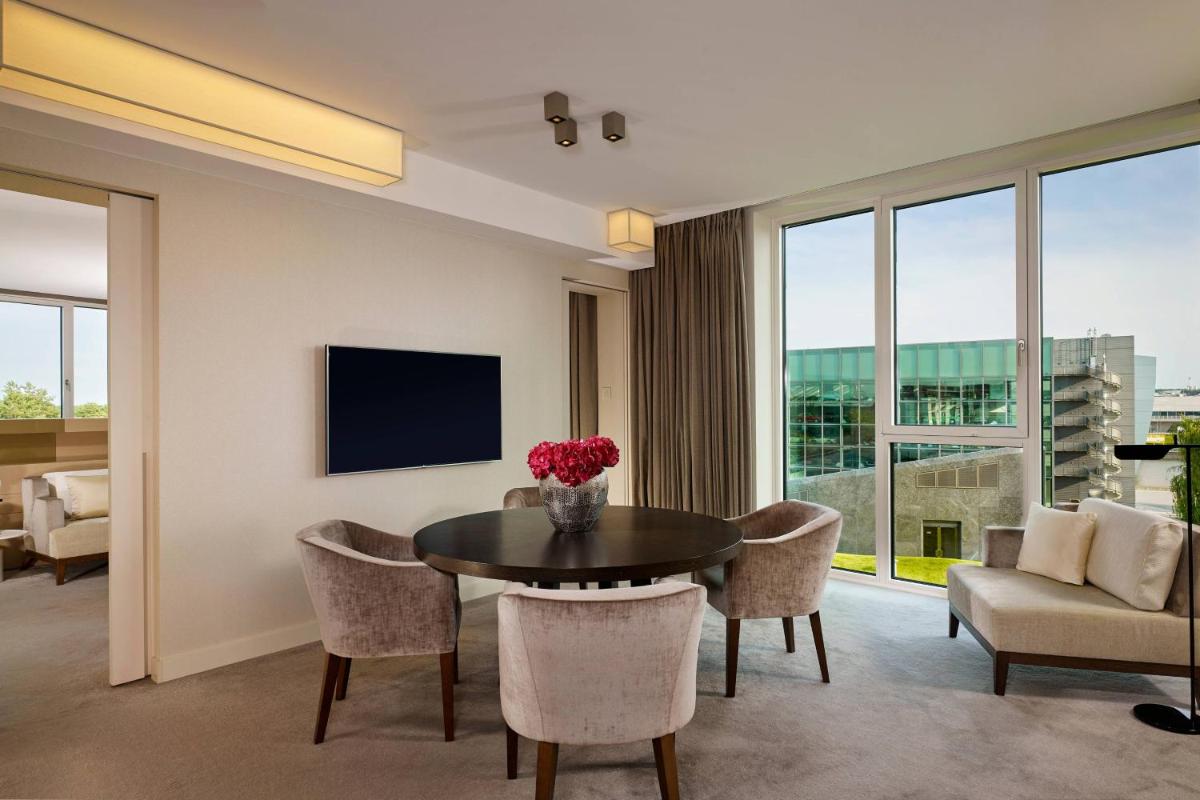ein Wohnzimmer mit Tisch und Stühlen und einem Fernseher in der Unterkunft The Ritz-Carlton, Wolfsburg in Wolfsburg