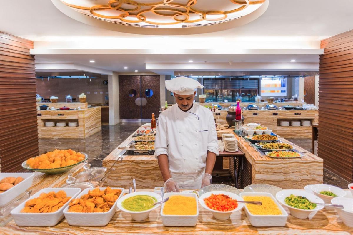 a chef standing in a kitchen preparing food at Crowne Plaza Ahmedabad City Centre by IHG in Ahmedabad